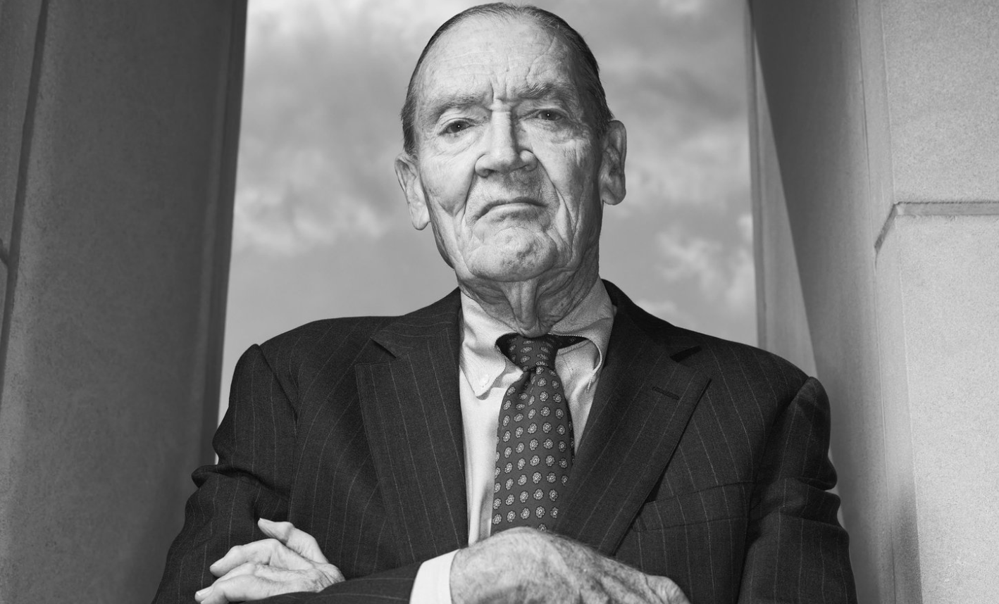 정장을-입고-팔짱을-낀-채 카메라를-응시하는-존-보글-가치-투자와-장기-금융-전략의-선구자로서-위엄을-나타내는-흑백-초상-이미지.