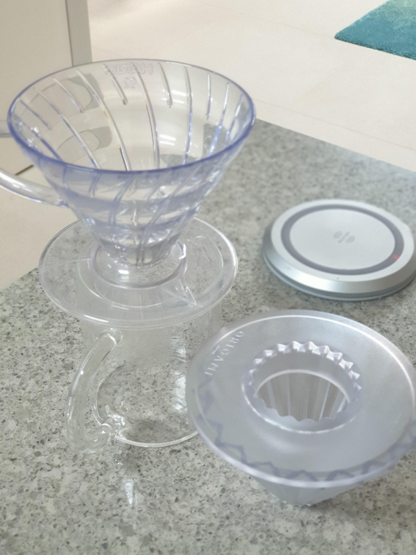 하리오 v60 드리퍼와 오리가미 드리퍼가 테이블 위에 놓여있다.