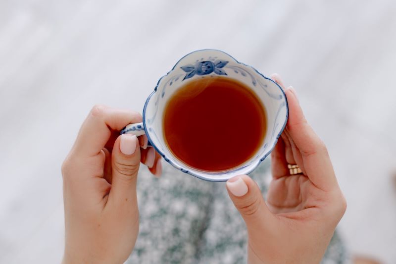 hands holding a cup of black tea
