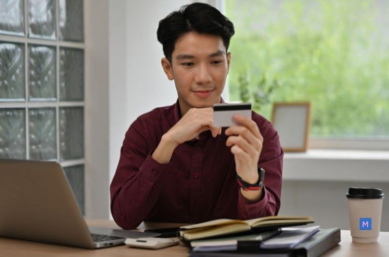 신용카드를 확인하는 사회초년생 직장인 - 신용등급 관리 실천 모습 via Canva