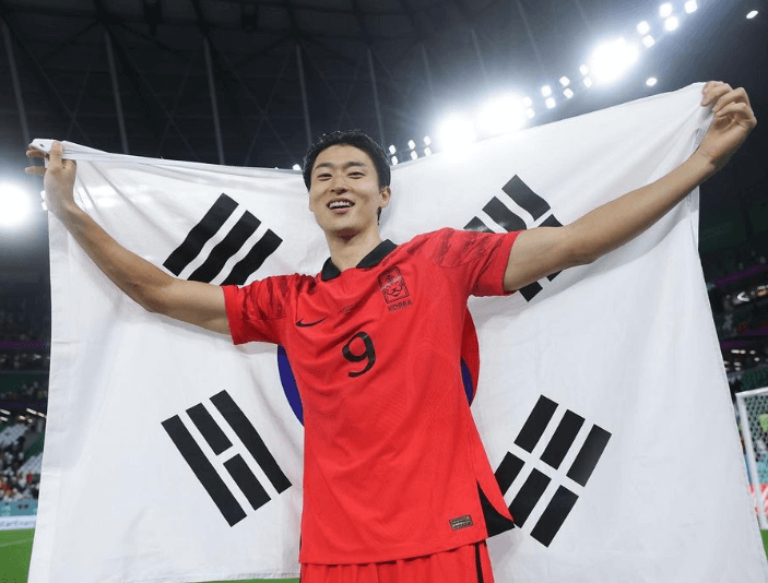 조규성 선수가 경기장에서 태극기를 등에 걸치고 기뻐하는 장면