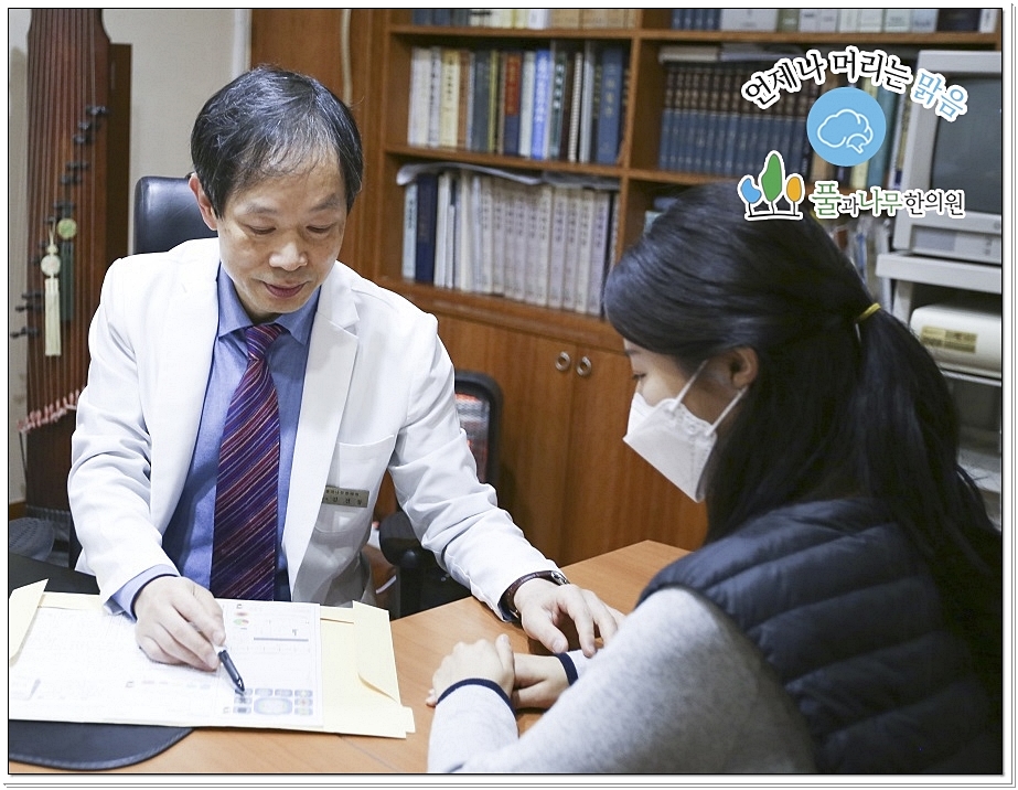 차트를 보며 진료 상담 중인 한의사와 환자의 모습