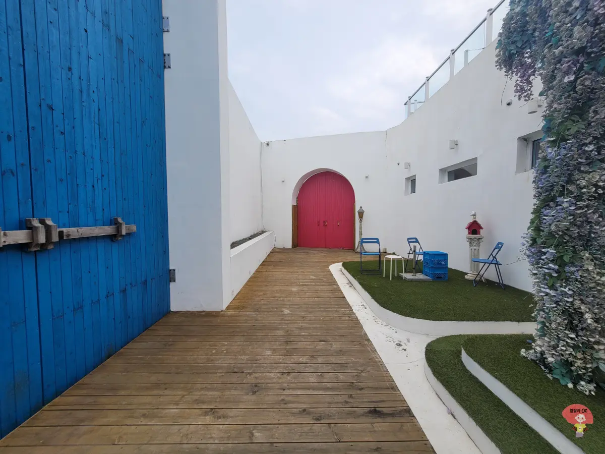 강원도-홍천-카페-테사로바-파란-나무문을-지나-하얀-벽과-붉은-아치문이-이어진-그리스-자킨토스-풍의-카페입구-풍경