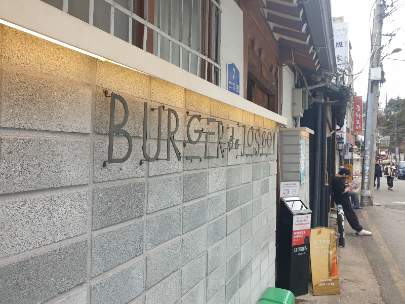 담에 철제로 BURGER DE JOSEON라고 쓰인 간판이 부착되어 있다.