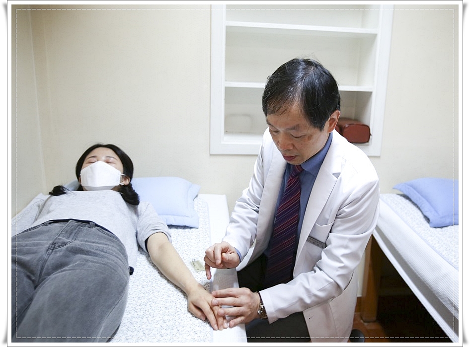 누워있는 환자의 손등에 침을 놓고 있는 한의사의 모습