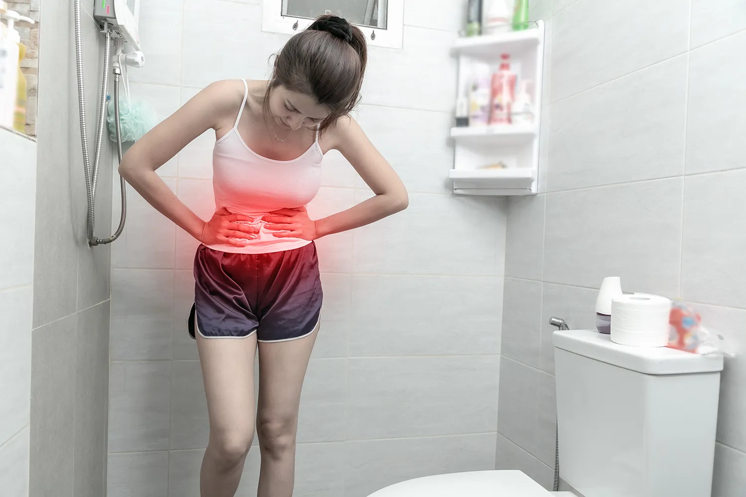 잦은 설사로 화장실에서 배를 움켜잡고 있는 여성