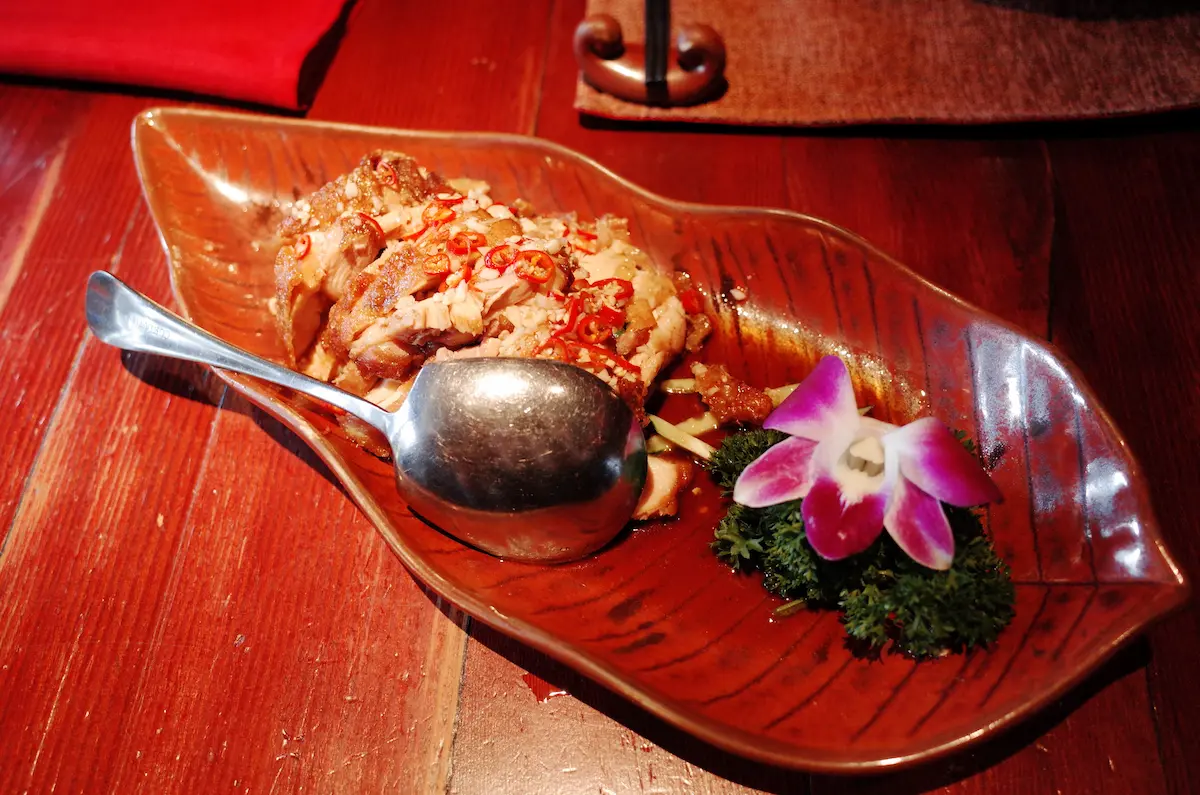 고추와 마늘 토핑이 올라간 매콤한 소스의 운남식 닭고기 요리와 화려한 난초 장식