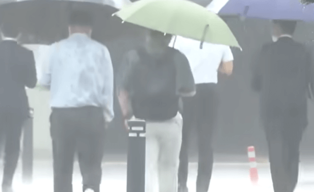 사람들이 우산을 쓰고 길을 건너는 장면