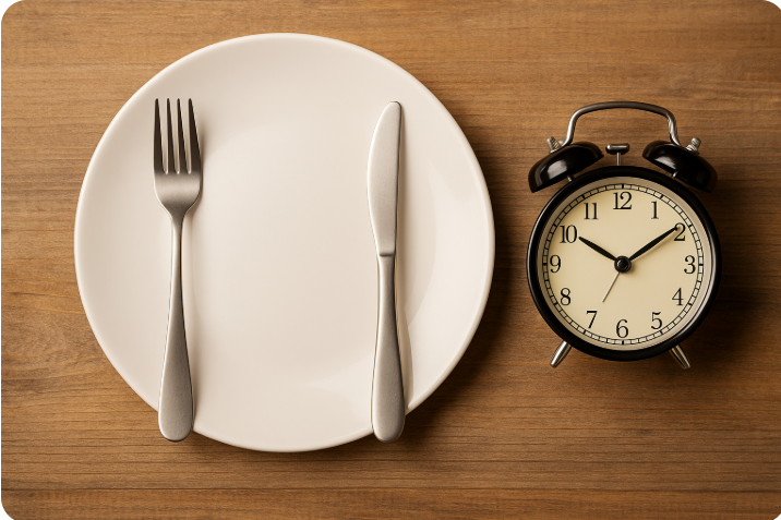 빈 접시 위에 포크와 나이프가 놓여 있고, 옆에는 자명종 시계가 놓여 있는 모습 – 간헐적 단식을 상징적으로 표현한 이미지