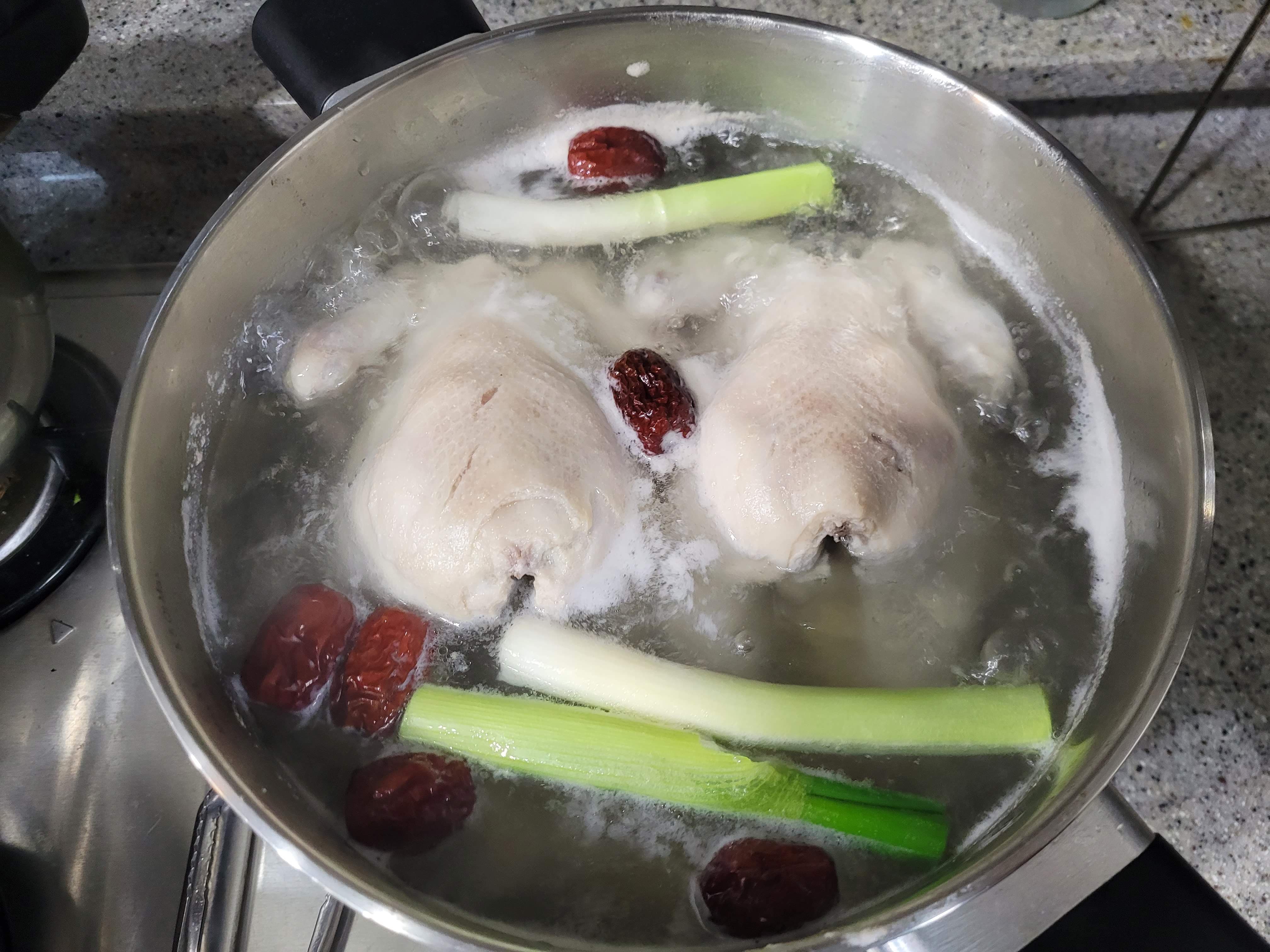 파 대추 마늘과 함께 냄비에서 끓고 있는 닭 두마리