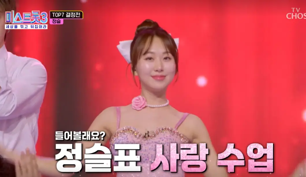 미스트롯3-빨간무대 앞 머리에 리본을 달고 분홍색 드레스를 입은채 미소짓는 정슬