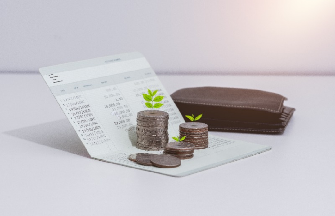 통장과 기 위에 동전이 쌓여있다. 그 뒤로는 갈색 지갑이 있다.