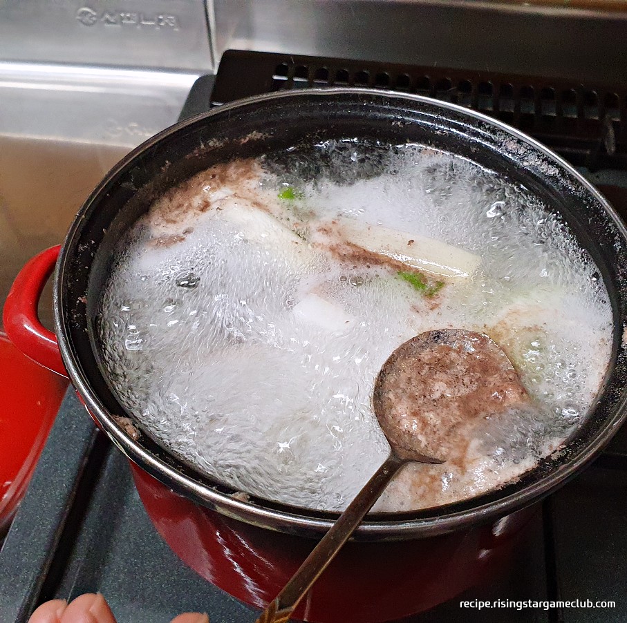 소고기 탕국을 끓이면서 뜬 불순물을 숟가락으로 제거하는 사진