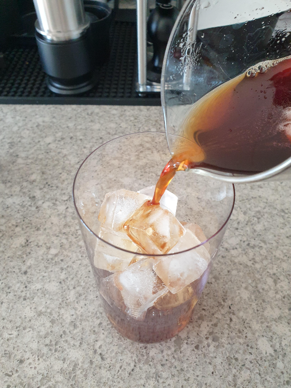 칠링된 커피를 얼음 컵에 붓는 모습