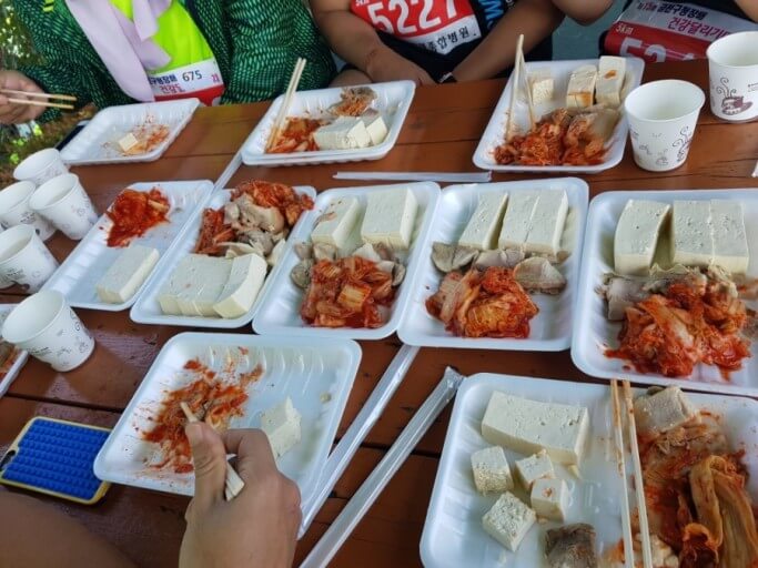 일회용 용기에 담긴 김치, 두부, 고기와 종이컵들