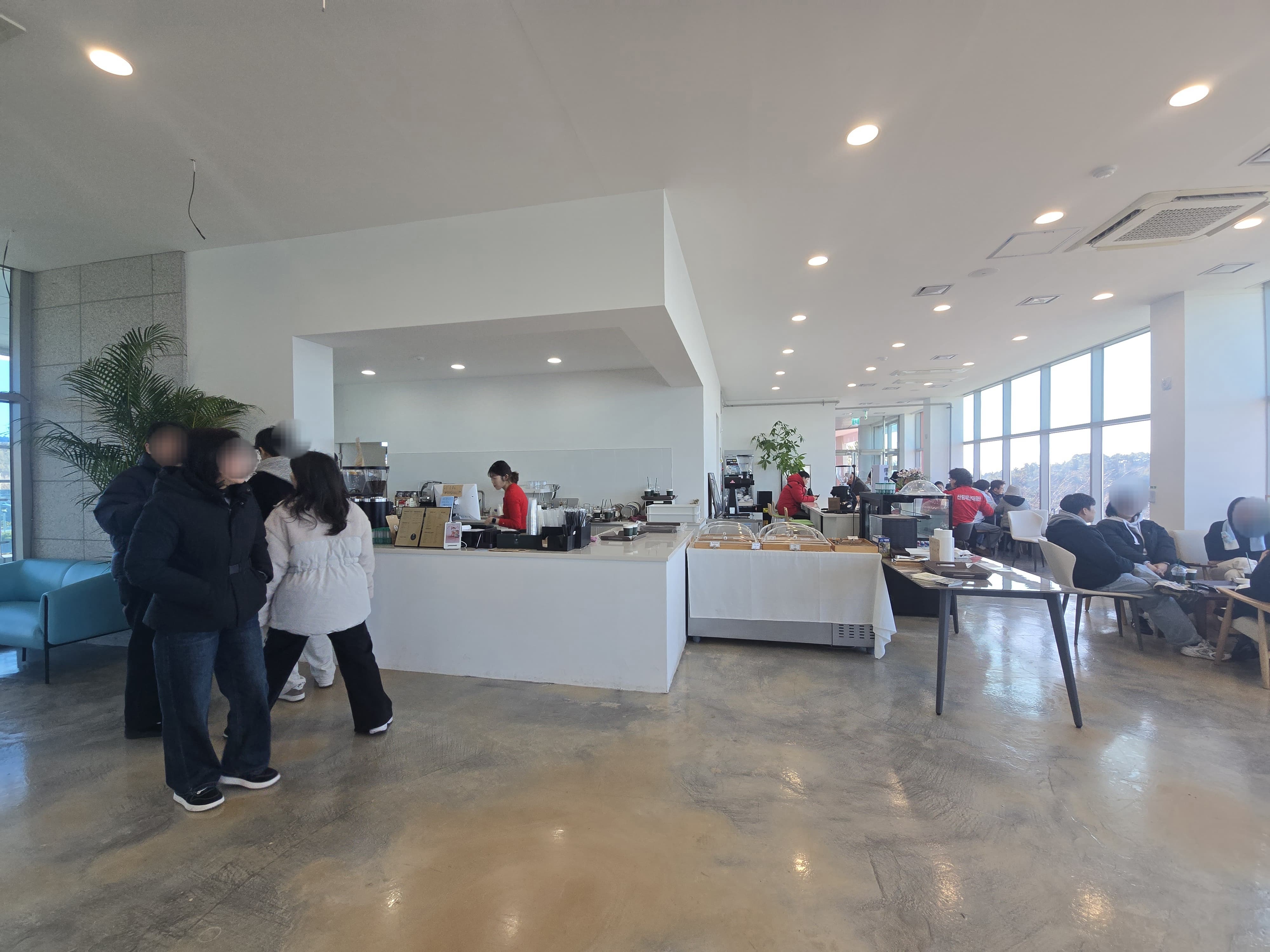 통창으로 된 엉클제이 카페안에 사람들이 테이블에 앉아서 커피를 마시는 모습