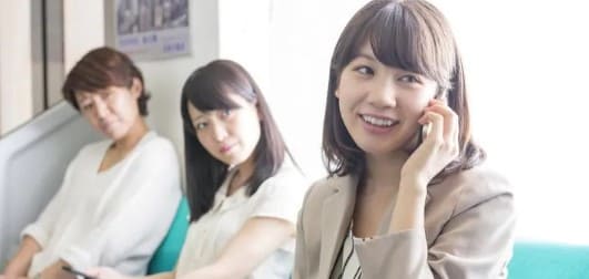 전철안에서 여성이 휴대폰으로 통화를 하고있고 나머지 승객 2명이 그 여성을 노려보고 있다.