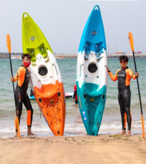 바닷가에서 카약과 노를 들고 있는 두 남자