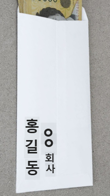 축의금 봉투 뒷면 왼쪽 하단에 '회사동료 홍길동'이라고 써있는 이미지. 정확한 이름 위치와 깔끔한 글씨가 돋보입니다.
