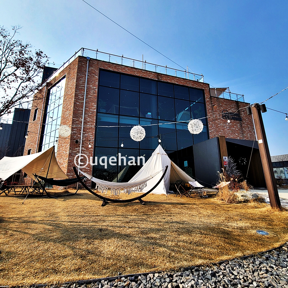 양주 백석 MOSSY CAFE 모씨 카페 외부사진이다. 건물 앞에 글램핑 느낌의 텐트들이 설치되어 있다.