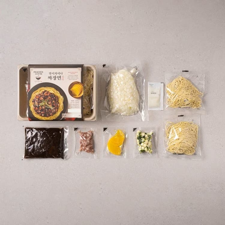 시판 짜장키트 포장과 그 안에 포함된 면, 소스, 건더기 스프 등이 펼쳐져 있는 모습