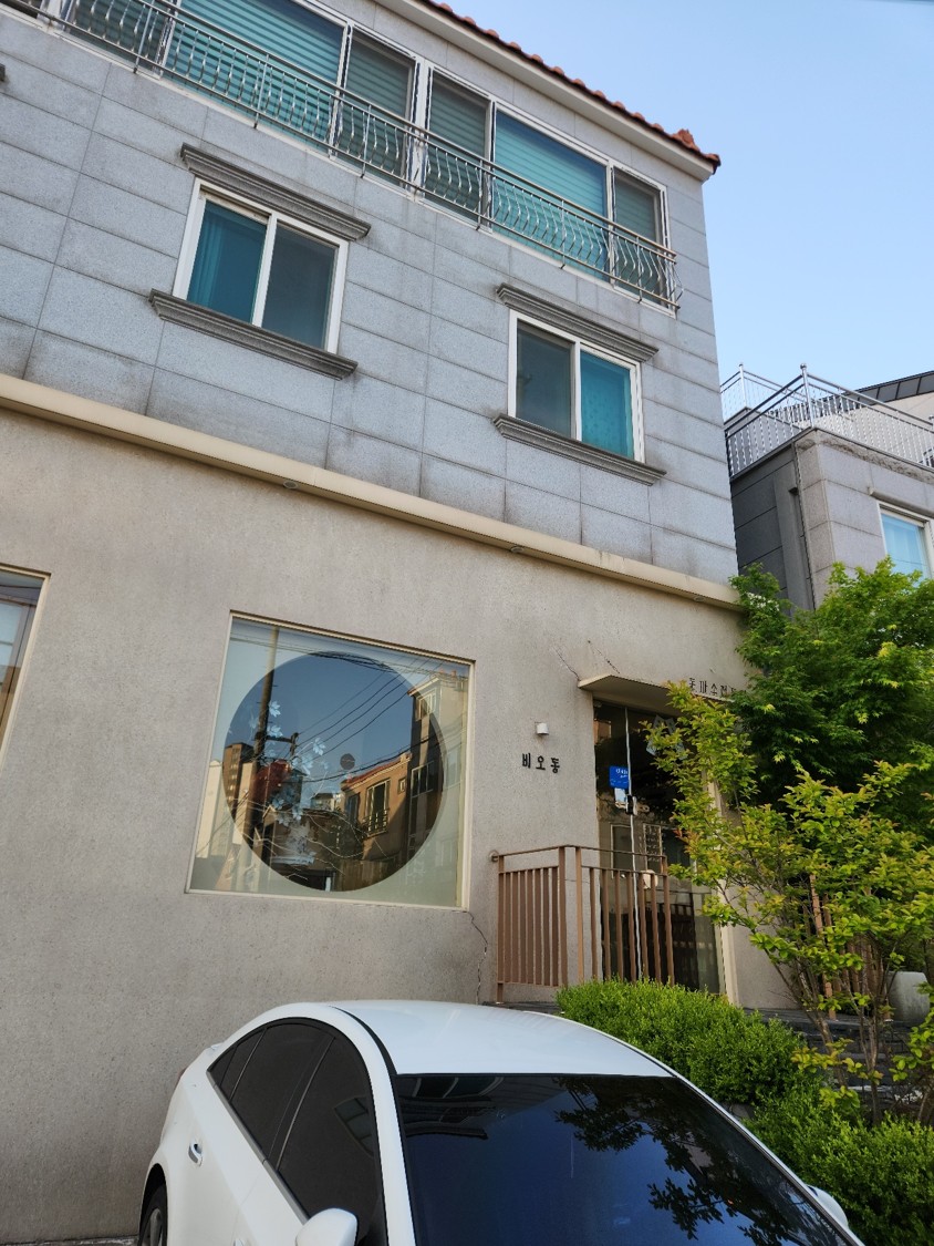 콘크리트 벽에 동그란 유리창으로 포인트를 준 돈까스 가게의 모습