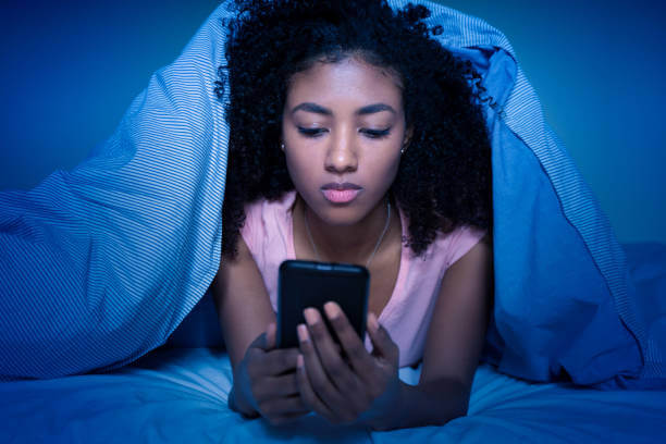 이불속에서 핸드폰을 들여다보고 있는 여성