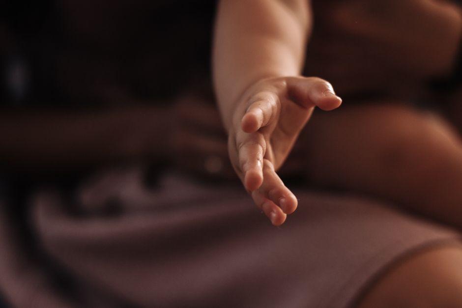 A baby's hand reaching out in a warm and tender moment.