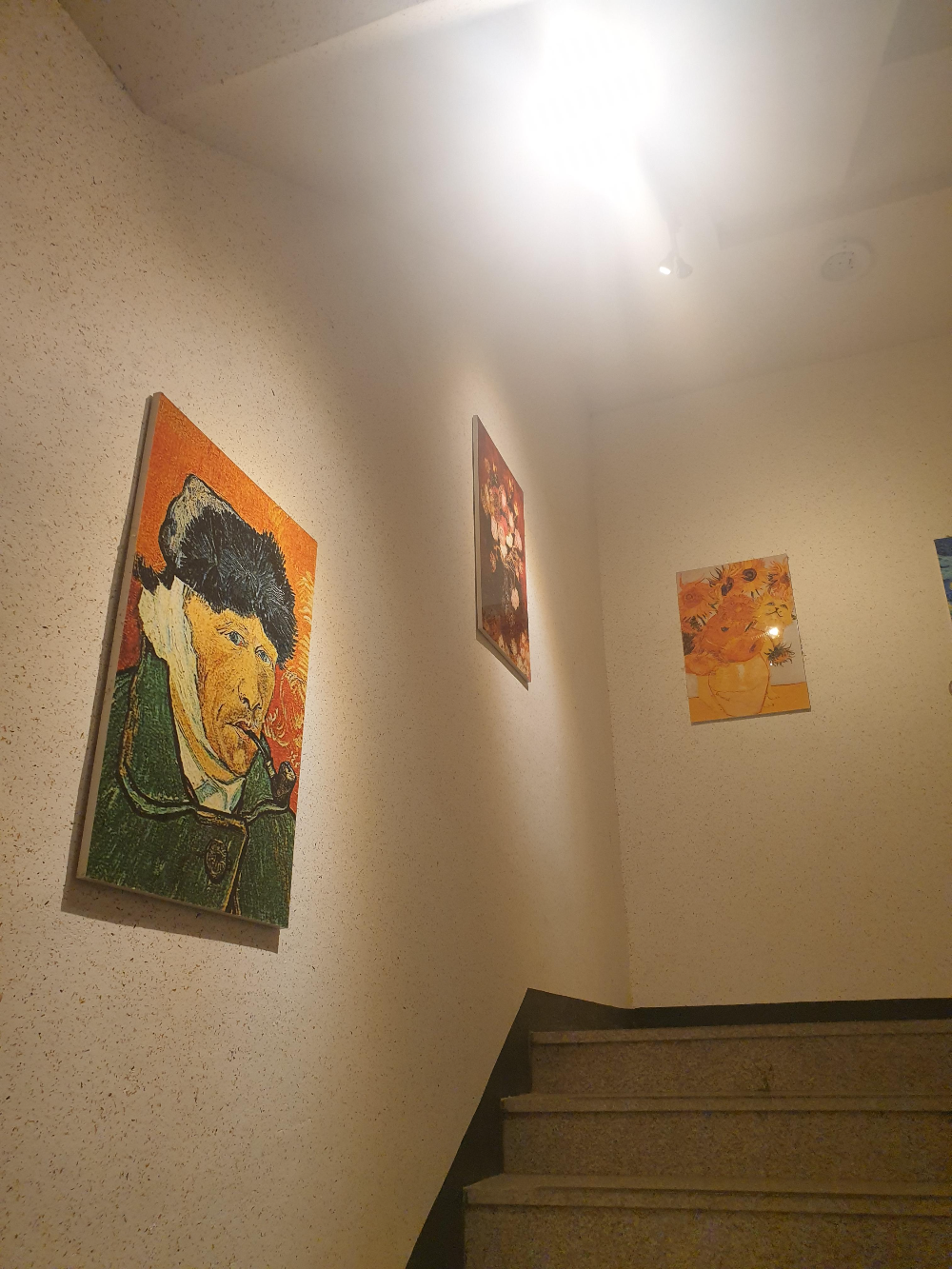 계단에 고흐의 그림이 걸려있다. 자화상, 해바라기 등