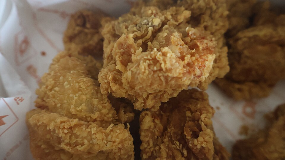 종이 위에 놓인 바삭한 한국식 후라이드치킨 조각의 튀김옷 질감을 가까이에서 찍은 사진