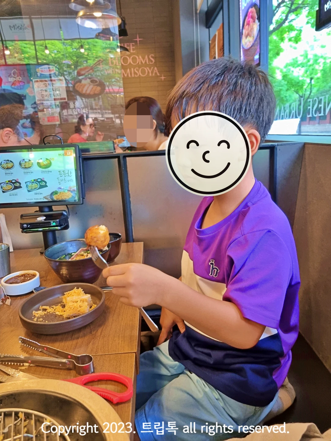 식당에 앉아서 돈까스를 포크로 집어서 먹고 있다.