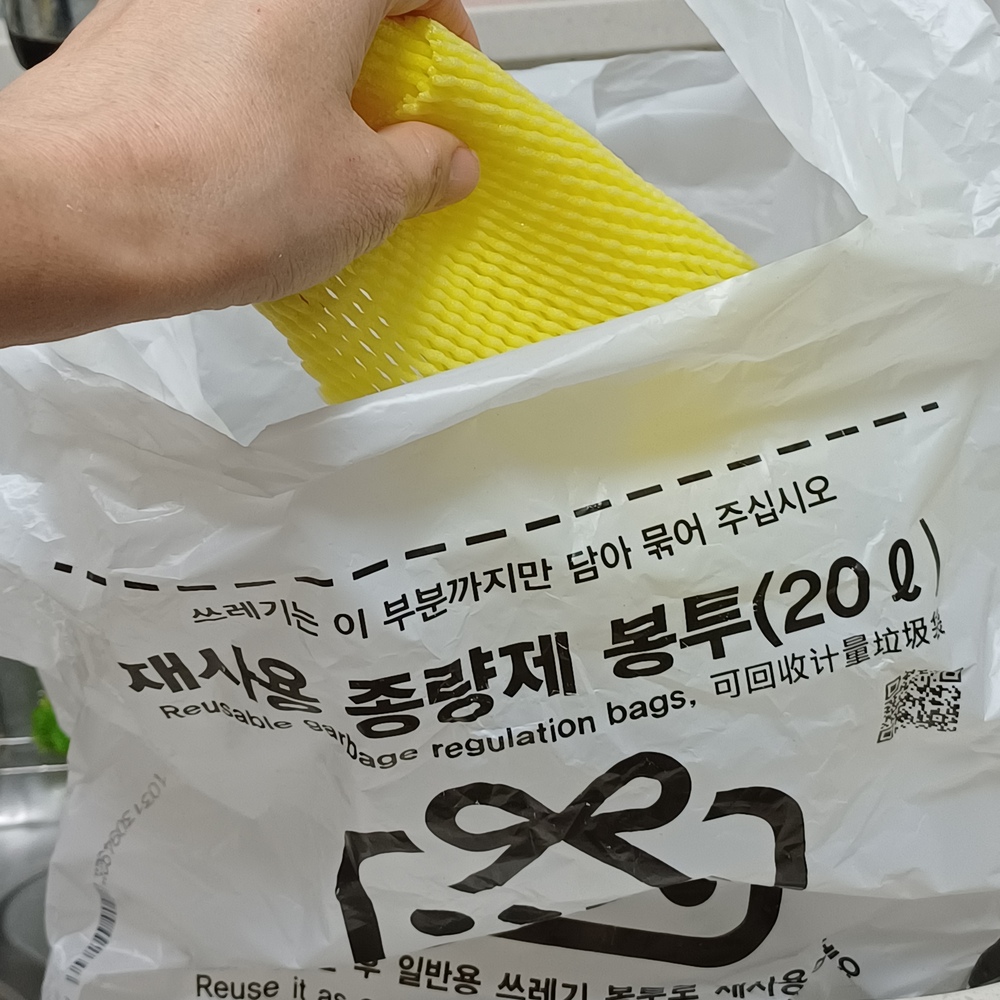 과일망을 종량제 봉투에 넣어 일반쓰레기로 정리하는 모습