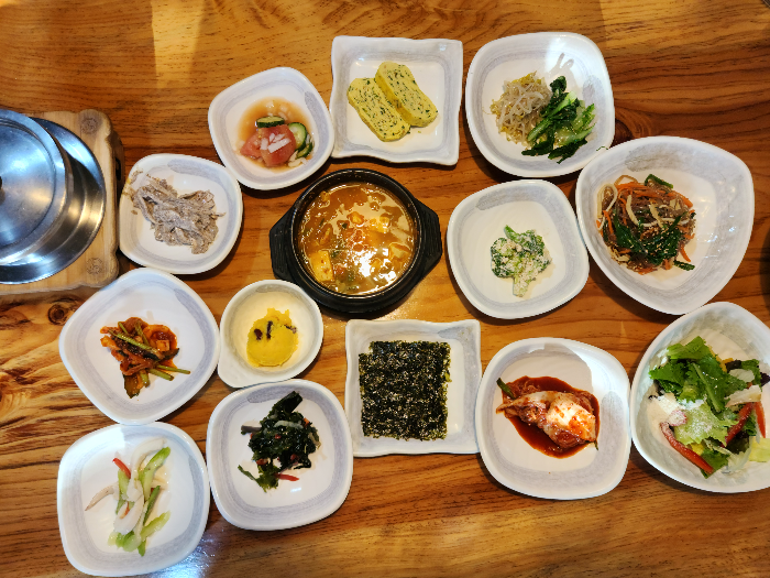 된장찌개와 김, 나물, 김치, 샐러드 등 10가지가 넘는 반찬이 담긴 접시가 테이블 위에 올려져 있다