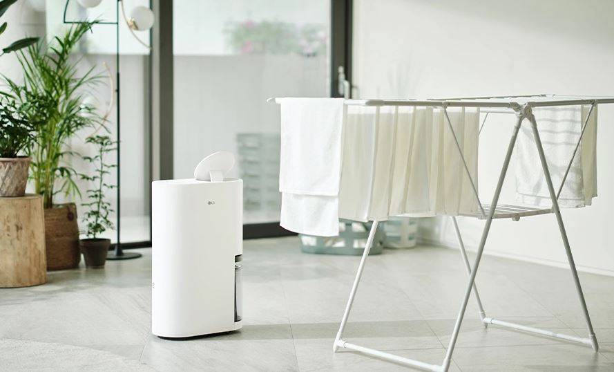 좌측에 화분4개, 그 우측에 lg 제습기, 그 우측에 건조대와 건조대에 널어놓은 수건10장