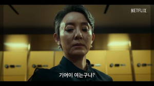 한 여성이 금고에서 무언가를 꺼내려 하고 있습니다.