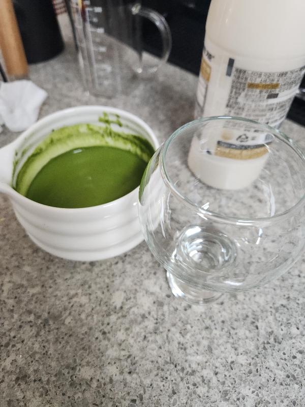 차완에 말차가 담겨 있다. 그리고 유리컵과 막걸리가 보인다.