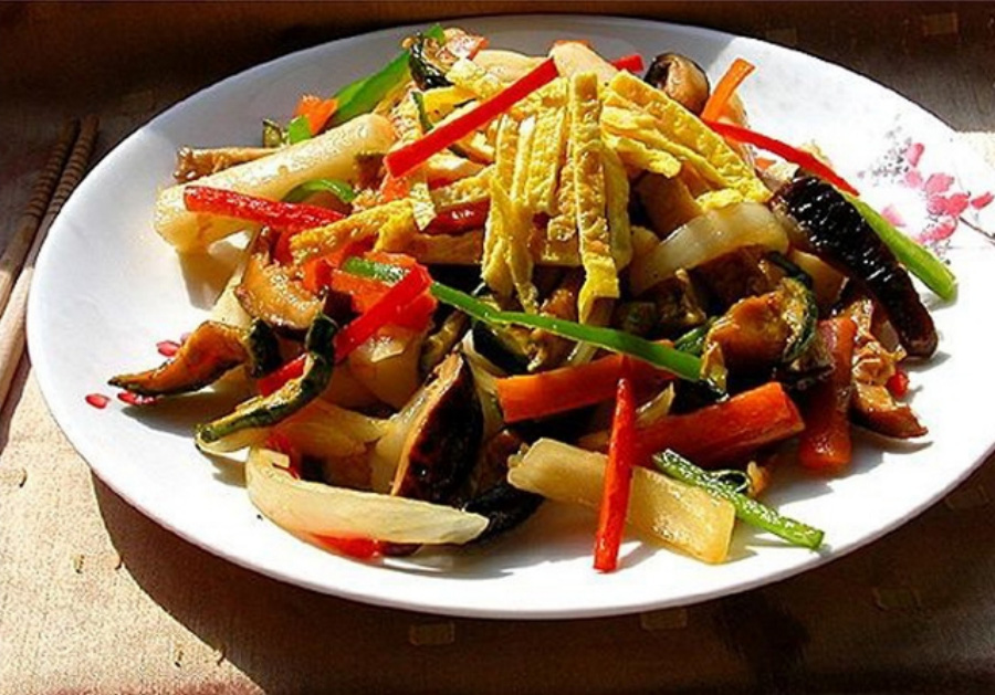 호박과 버섯, 돼지고기, 고추, 양파, 떡을 넣고 만든 호박고지 궁중떡볶이를 동그랗고 하얀 접시에 가득 담아두고 찍은 사진