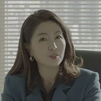 어느 사무실을 배경으로 파랑 정장에 갈색 긴머리를 하고 앉아 있는 드라마 순정복서의 이영애 캐릭터