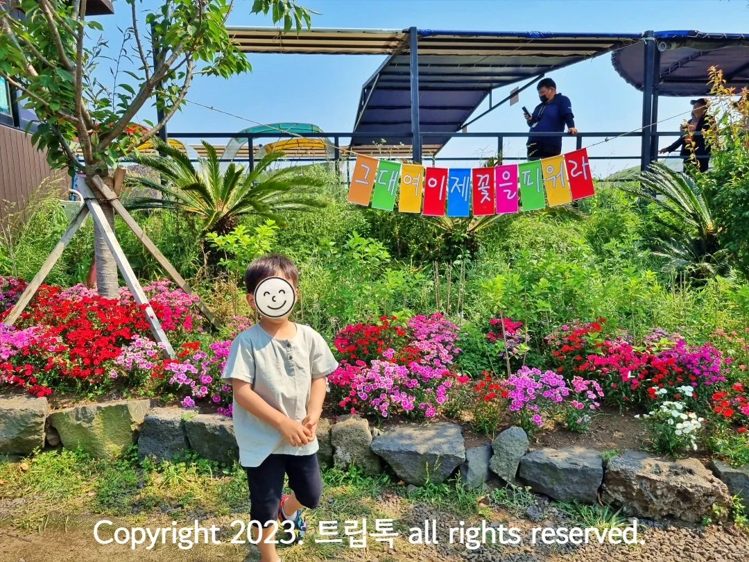 철쭉과 무지개 가랜드 앞에 선 아이