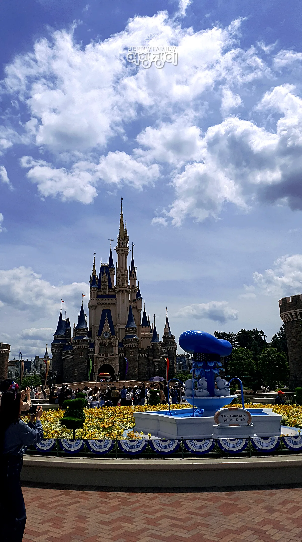 &quot;Cinderella Castle and Donald Duck-themed fountain at Tokyo Disneyland under blue sky&quot;