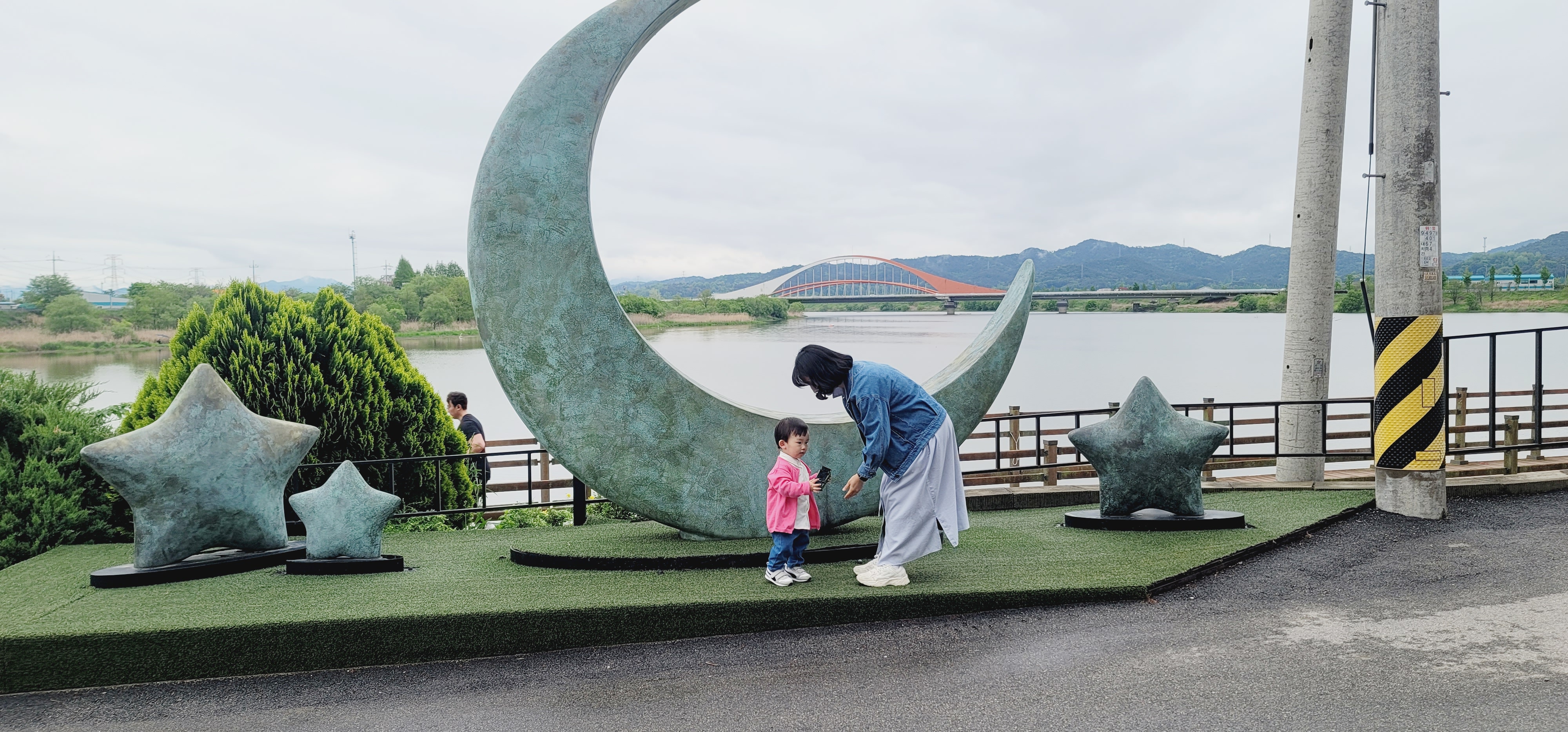 달모양의 대형 인테리어 모형앞에 허리를 숙인 엄마와 3살짜리 아기가 마주보고 있는 다정한 모습