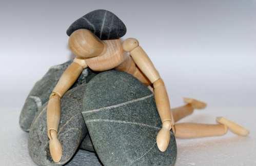 교사를 위한 청소년 상담 지도 방법 (상담, 프로그램, 사례), 돌무더기에 눌려있는 사람 나무 인형 사진