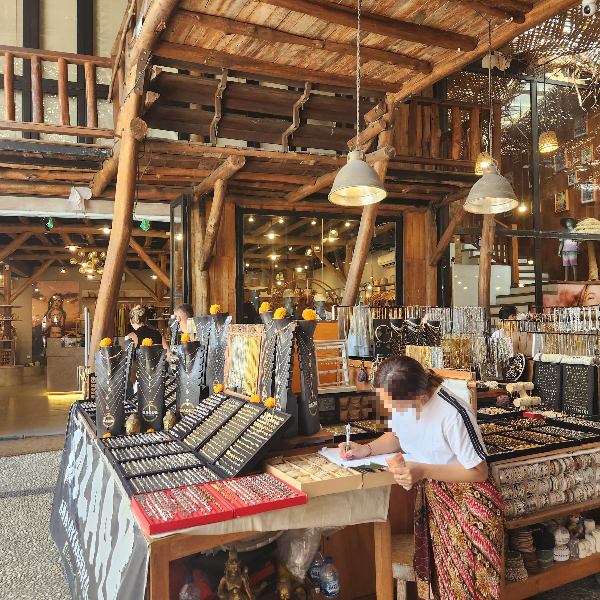 Love Anchor Canggu 시장 내부 목제로 된 기둥 그리고 악세서리 가게 점원이 일을 하고 있다.