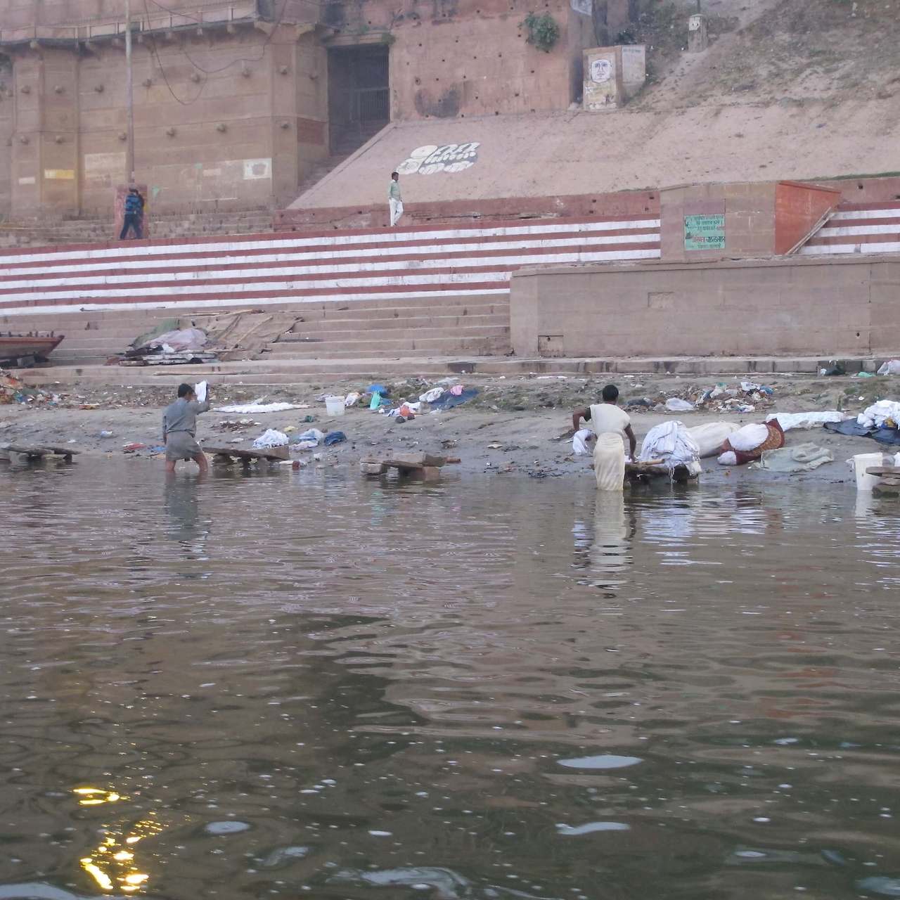 갠지스강 가트(계단) 아래 혼탁한 강물 속에서 현지인들이 몸을 담그고 목욕하거나 빨래를 하는 모습