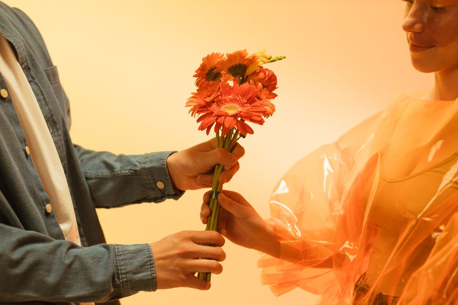 A serene moment of exchanging a bouquet of flowers between two people in a warm ambient light.