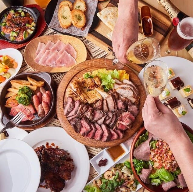 테이블 위에 많은 음식들이 있고 그 위로 샴페인 잔을 잡고 있는 두 손이 있다