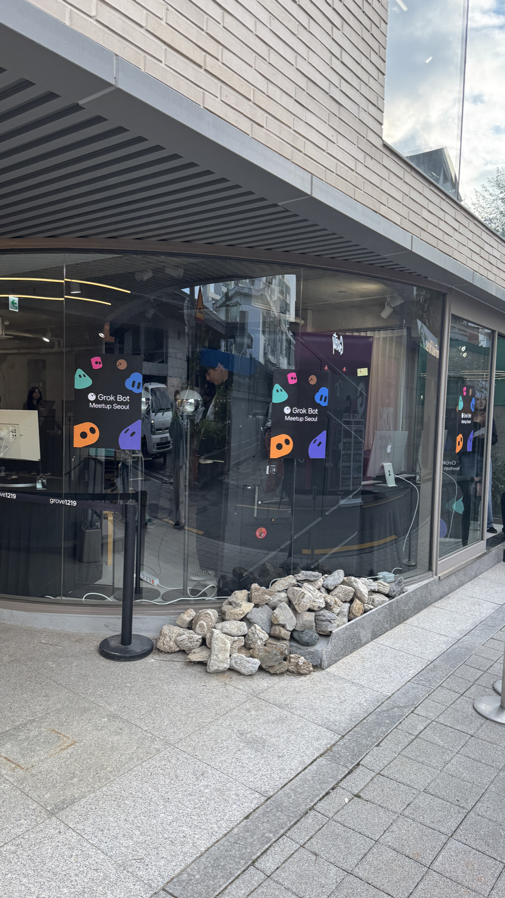 유리 외벽과 Grok Bot Meetup Seoul 포스터가 보이는 GROVE 1219 입구 전경