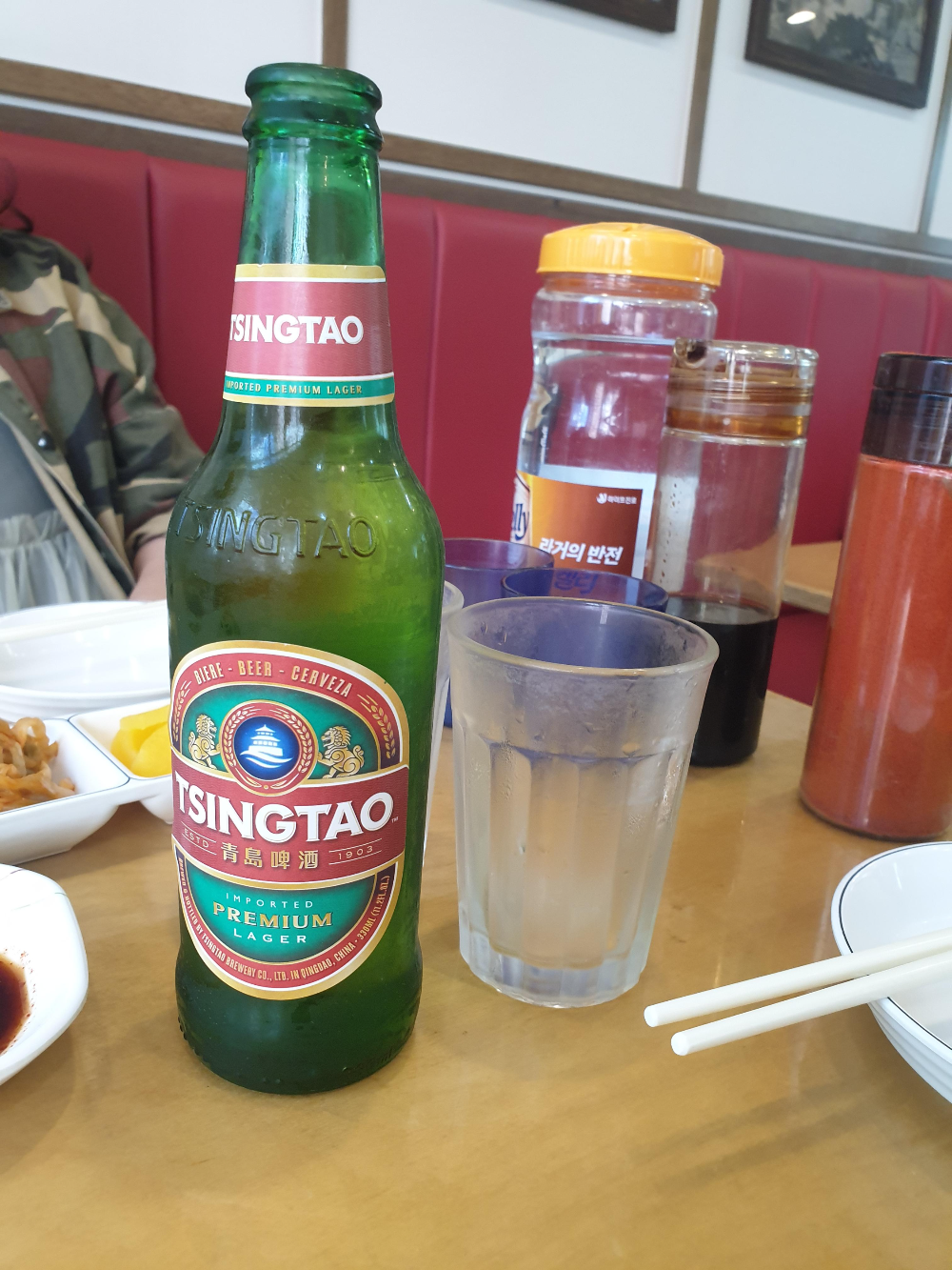 칭다오 맥주와 물병 그리고 컵들이 보인다. 식초와 고추가루도 있다.