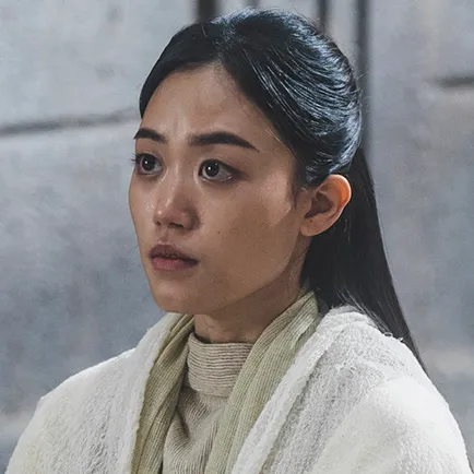 긴머리를 뒤로 살짝 묶어 내려 트린 20대 여성이 흰 사제복을 입고 앉아 있는 아라문의 검 소진 캐릭터