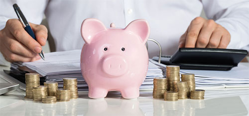 서류에-사인하는-남자-앞에-동전과-분홍색-돼지저금통이-놓여있음